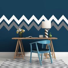 a desk with a chair and lamp in front of a wall painted with chevron stripes