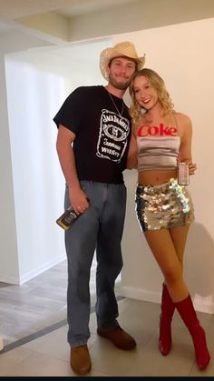 a man standing next to a woman wearing short shorts and cowboy boots in front of a white wall