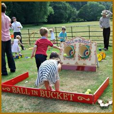 children playing in an outdoor play area with balls and buckets on the ground while adults watch