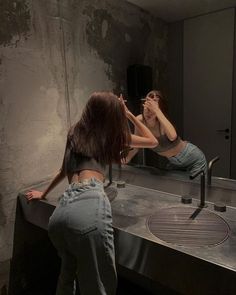 two women standing in front of a mirror brushing their teeth