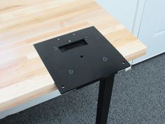 a wooden table with black metal legs and a square hole in the center on top