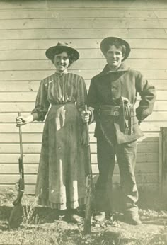 an old black and white photo of two people standing next to each other holding shovels