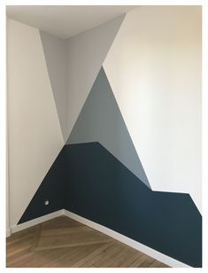 an empty room with a painted triangle on the wall and wood flooring in front of it