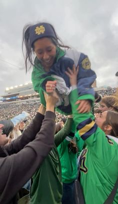 a woman holding a child in her arms at a football game