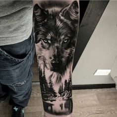 a man's arm with a wolf and trees tattoo on the left side of his leg