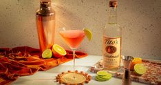 a table topped with bottles and glasses filled with alcohol next to a tray full of limes