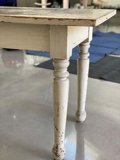 an old white table sitting on top of a hard wood floor