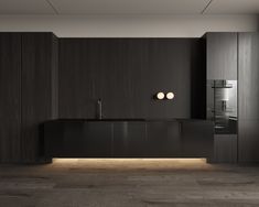 a modern kitchen with black cabinets and wood flooring