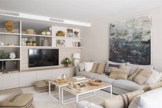 a living room filled with furniture and a flat screen tv mounted on a wall above a wooden coffee table