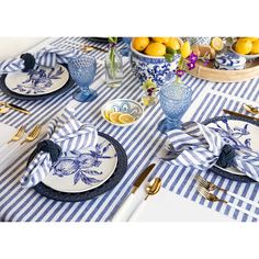 the table is set with blue and white plates, silverware, and lemons