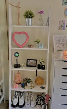 there is a shelf with shoes and pictures on it in the corner next to a dresser