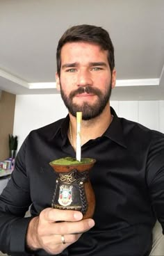 a man sitting down holding a cup with a candle in it