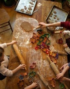 children are making cookies on a wooden table