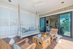 an outdoor living area with swing chairs, table and couch in front of sliding glass doors