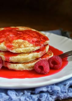 a stack of pancakes with raspberries and syrup