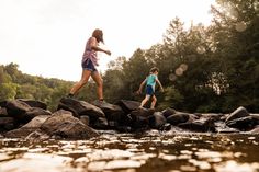 two people are running across rocks in the water