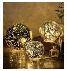 three decorative lights sitting on top of a wooden table next to bottles and vases