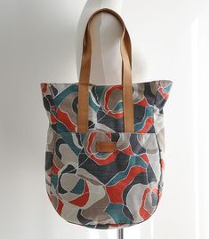 a multicolored tote bag hanging on a white mannequin