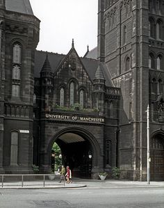 two people walking in front of an old building