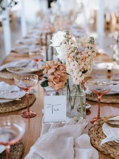 the table is set with place settings and flowers in glass vases on each side