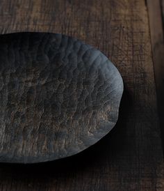 a black plate sitting on top of a wooden table