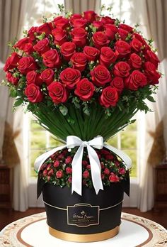 a large bouquet of red roses in a black box on top of a white table