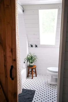 a white toilet sitting in a bathroom next to a wooden door with a potted plant on it