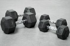 three black dumbbells sitting next to each other on a gray surface with white trim