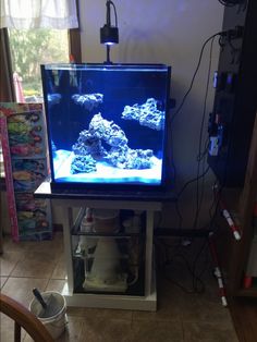 a fish tank sitting on top of a table next to a wall mounted tv screen