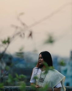 a woman is standing in the grass with her hand on her hip and looking off into the distance