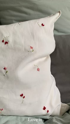 a white pillow with red flowers on it and the words love it written in cursive writing