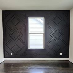 an empty room with black painted walls and wood floors