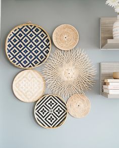 four woven baskets are hanging on the wall next to two books and a vase with flowers