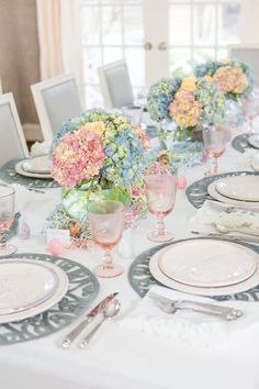 the table is set with white and blue plates, silverware, and flowers in vases