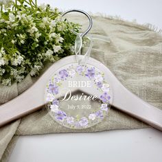 a personalized hanger with flowers on it next to a bouquet of white and purple flowers