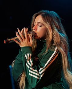 a woman with long hair is holding a microphone in her hand and singing into the microphone