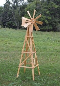 a wooden windmill sitting on top of a lush green field