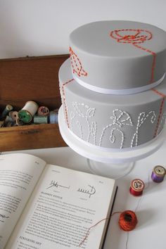 a three tiered cake sitting on top of a table next to an open book