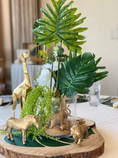 a table topped with figurines and greenery on top of a wooden slab