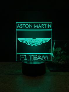 an illuminated sign with the name and logo on it in front of a bowl of rocks