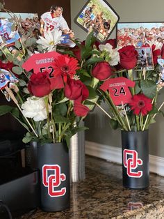 two vases filled with flowers on top of a counter next to pictures and photos