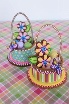 there are two small baskets with flowers in them on the checkered tablecloths