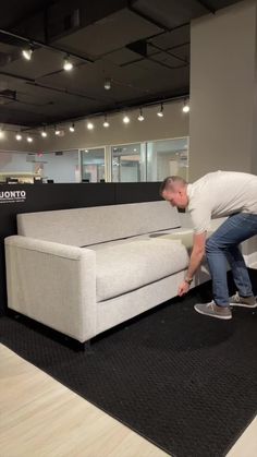 a man bending over to pick up a couch