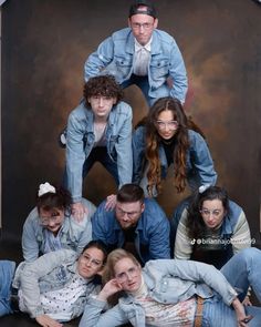 a group of young people posing for a photo in denim jackets and jeans on the floor