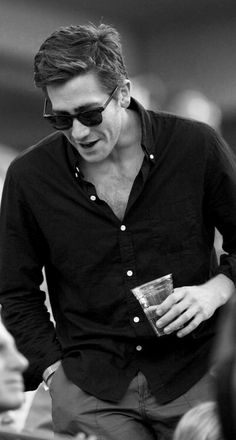 a man wearing sunglasses and holding a drink