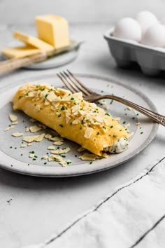 an omelet is sitting on a plate next to some eggs and silverware