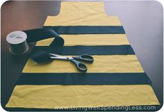 a pair of scissors sitting on top of a yellow and black piece of cloth next to a roll of tape