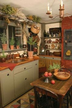 an old fashioned kitchen with lots of pots and pans on the counter top, surrounded by potted plants