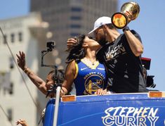 a man and woman kissing in the back of a blue truck with people standing around