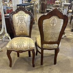 two chairs sitting next to each other in a room filled with furniture and mirrors on the floor